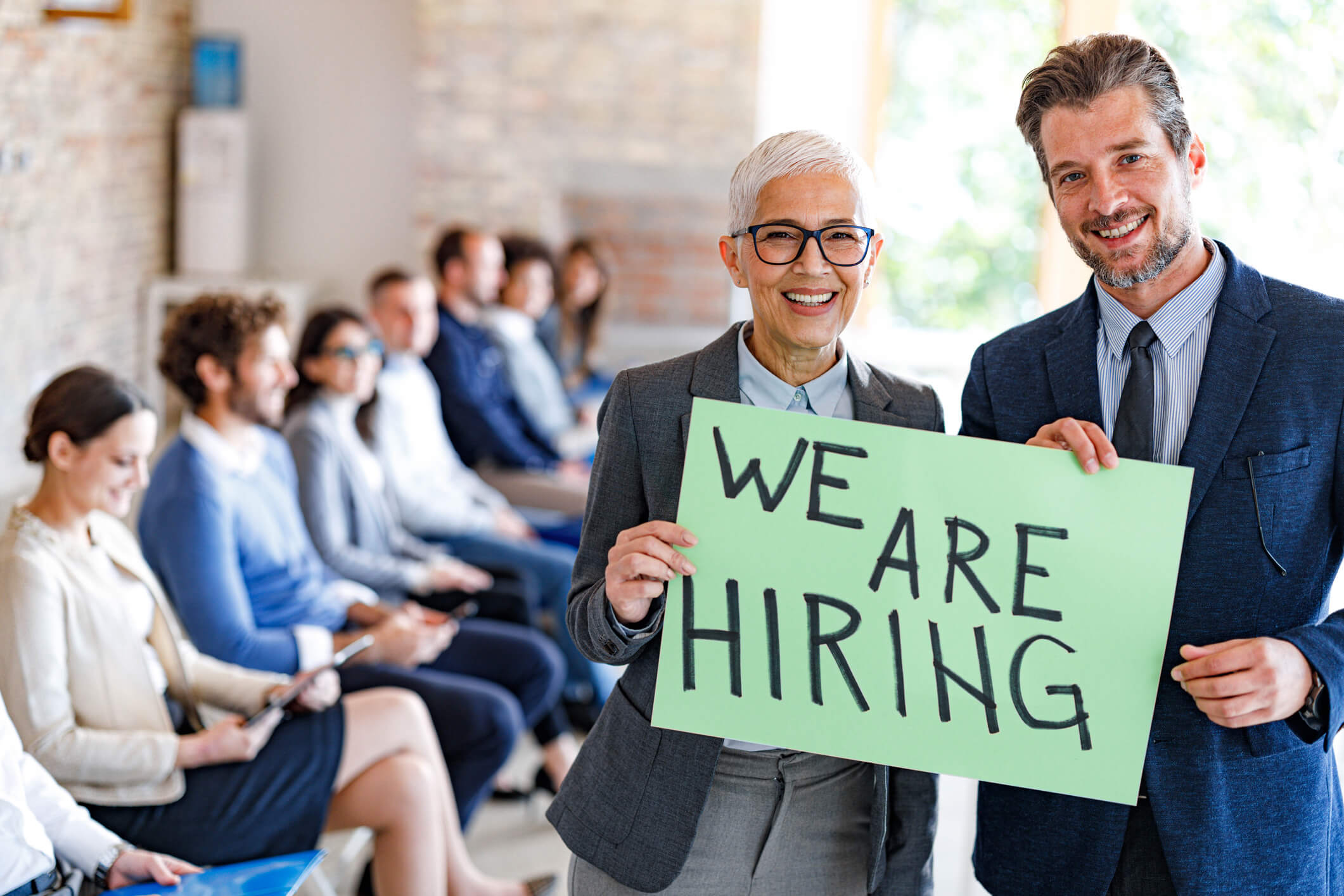 Professionals holding "We Are Hiring" sign