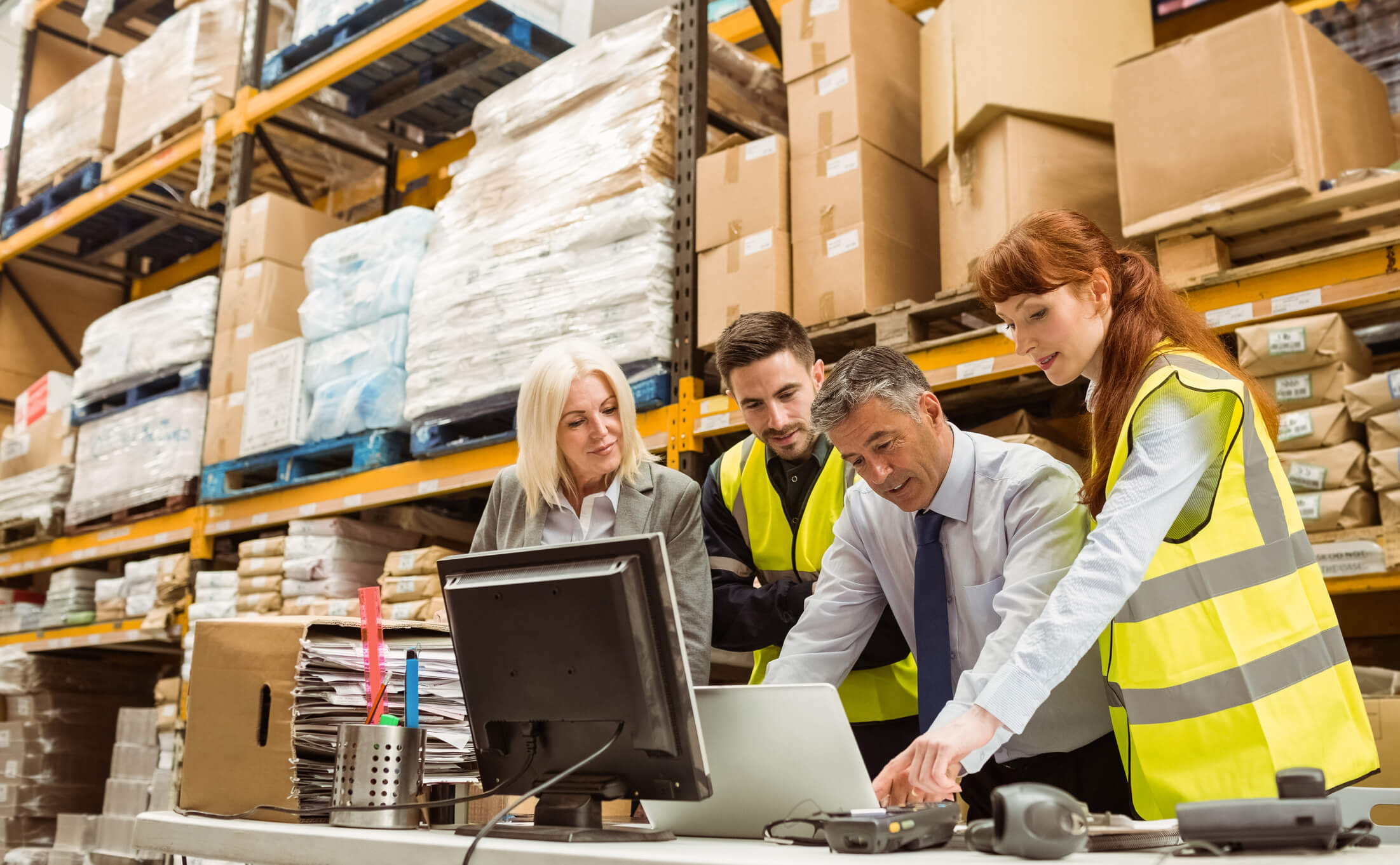 Warehouse team discussing logistics at computer